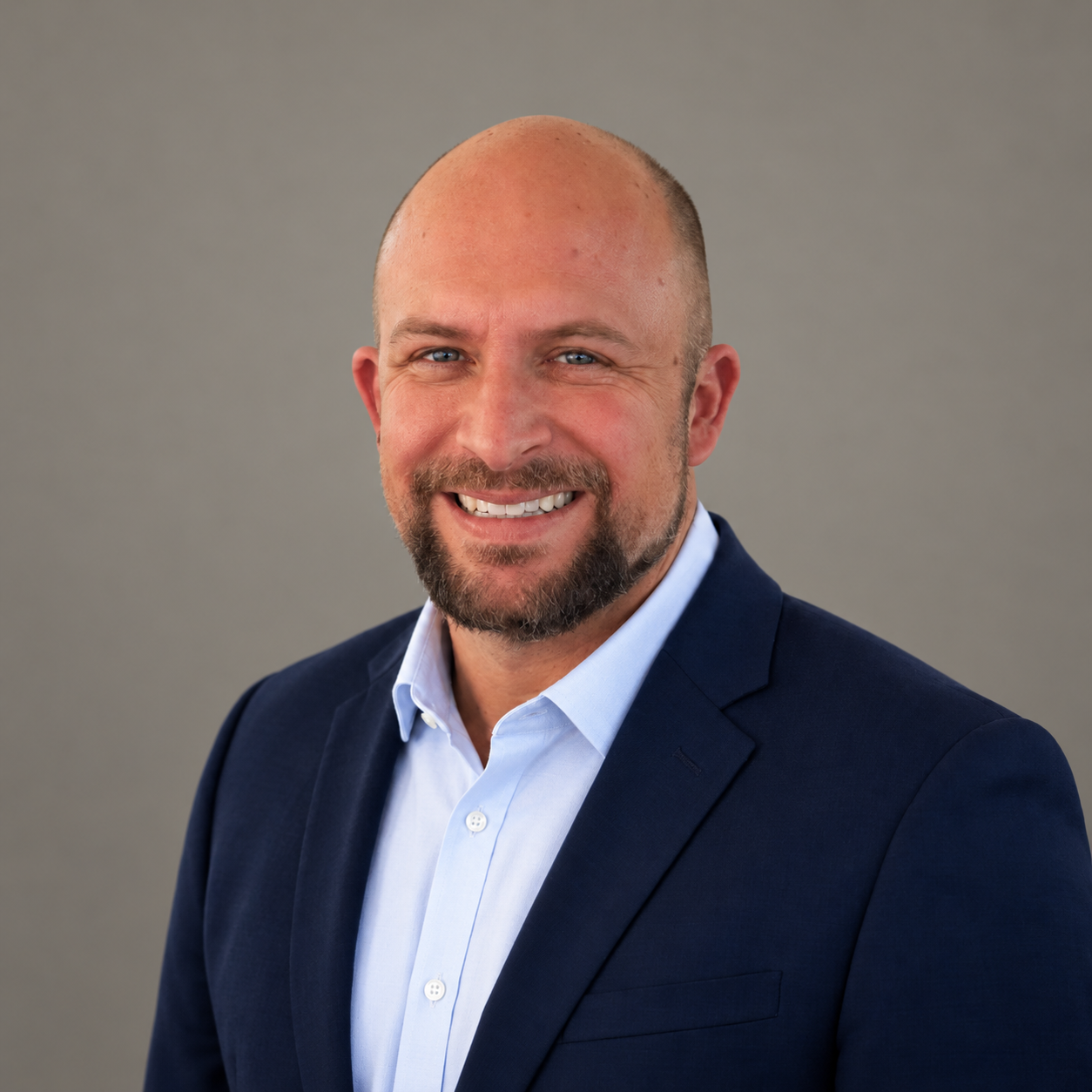 Devin Hutchings smiling, wearing a navy blazer and light blue shirt